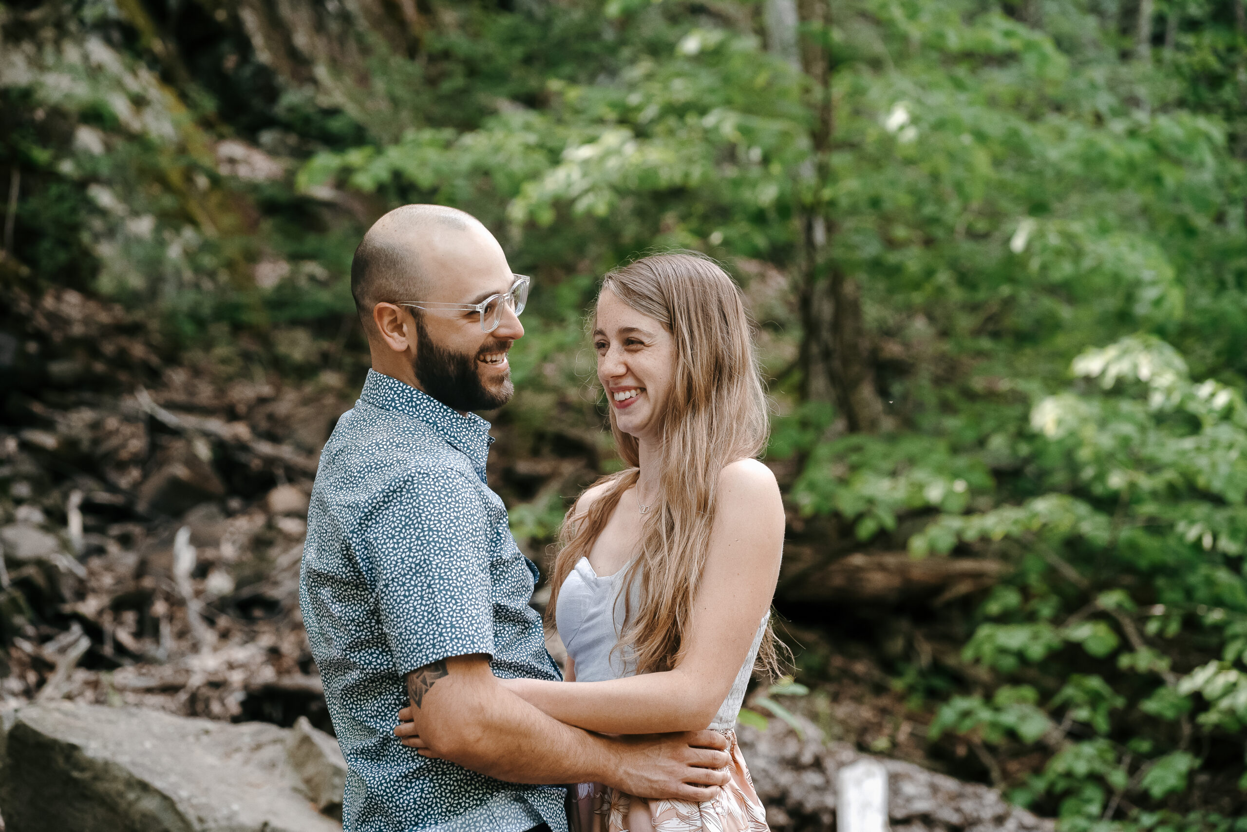 Engaged couple laughing in woods