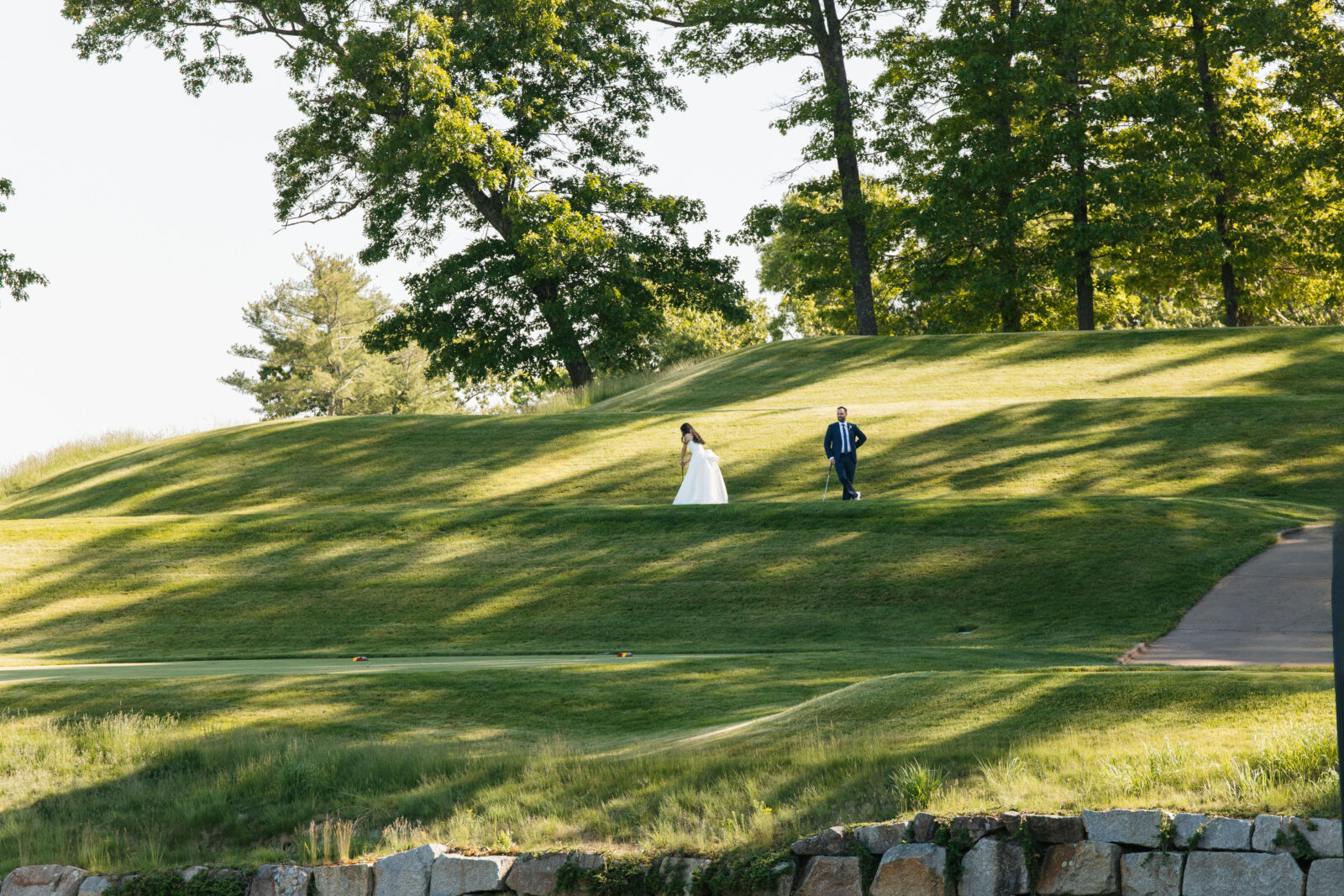 
A special moment as Alix and Wiley tee off together at the 10th hole of Turner Hill, just after their ceremony. Surrounded by family and friends watching from the ceremony site, this unique moment reflects their love for the club and adds a personal touch to their wedding day.