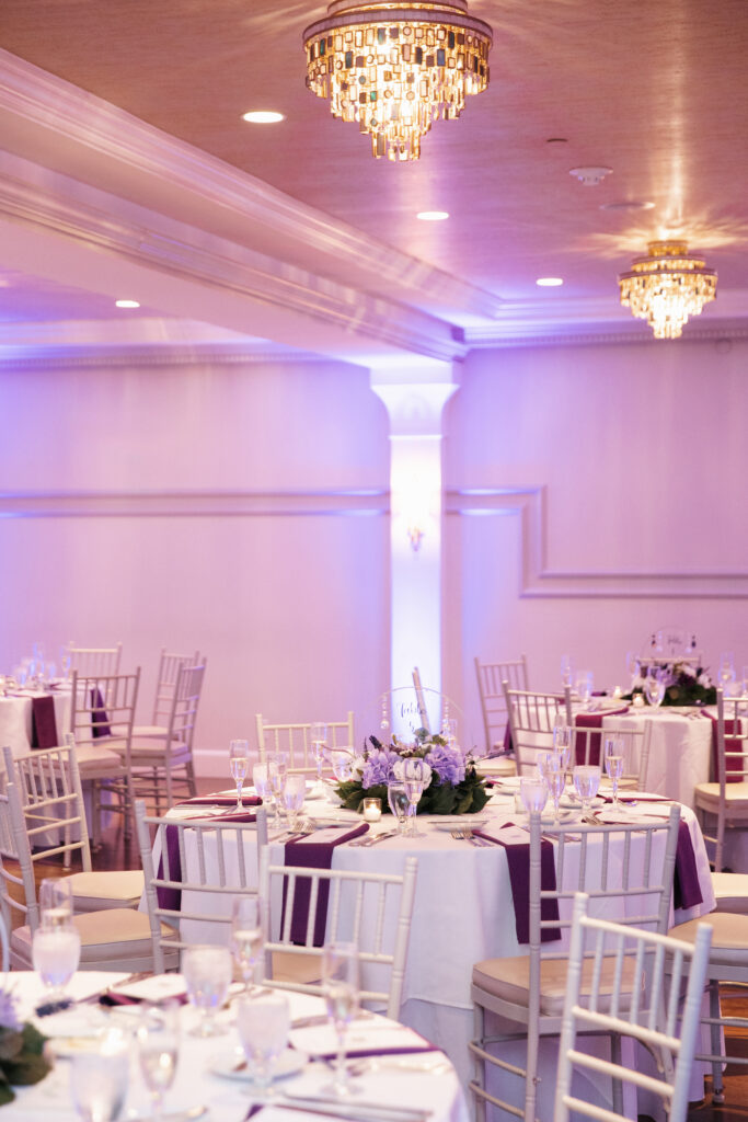 A beautiful shot of a wedding reception at Saphire Estate in Sharon, with elegant floral arrangements and sparkling chandeliers illuminating the grand ballroom. The sophisticated space is filled with soft, warm lighting, creating an intimate and luxurious atmosphere. The venue’s timeless architecture and stunning decor provide the perfect backdrop for a celebration full of joy and elegance.