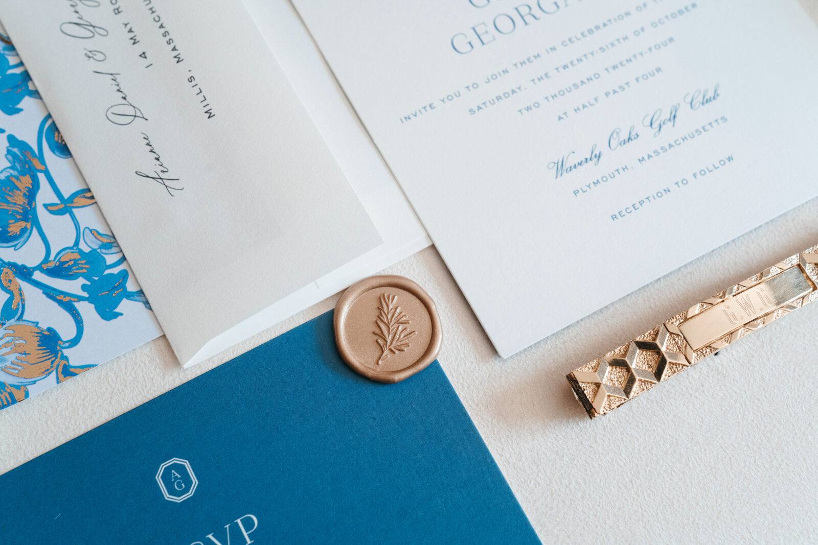 Elegant wedding flat lay with invitation suite, rings, and florals styled on soft linen at Waverly Oaks in Plymouth, MA.