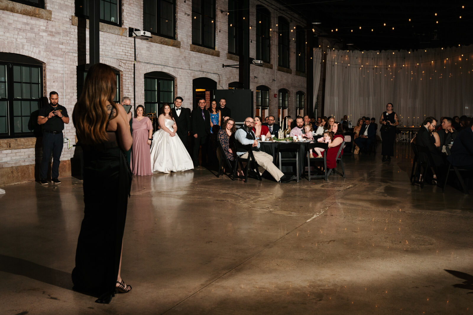 Wedding reception dance floor with guests dancing, including friends in blow-up suits, celebrating to Bad Bunny’s music.