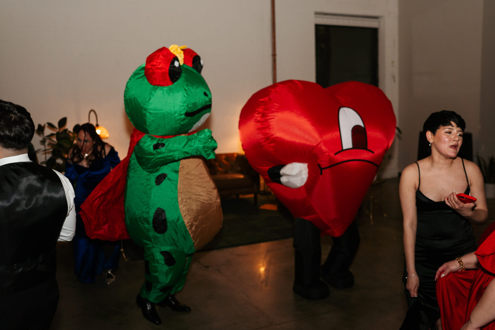 Wedding reception dance floor with guests dancing, including friends in blow-up suits, celebrating to Bad Bunny’s music.