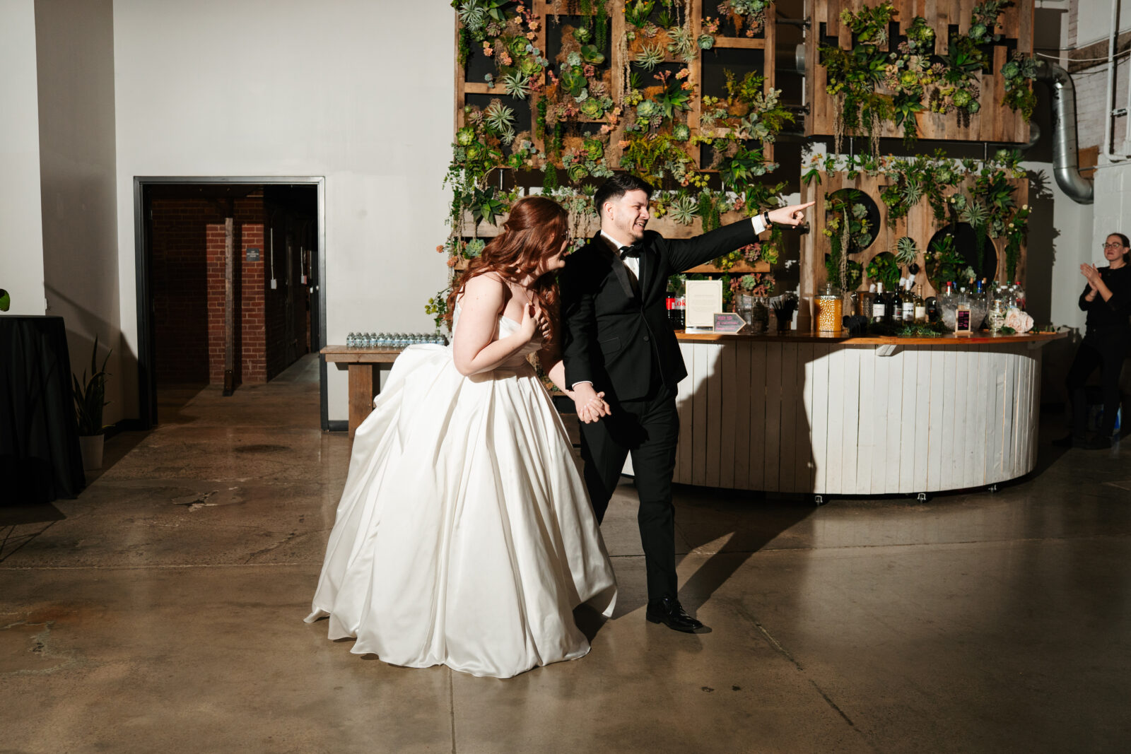 Wedding reception dance floor with guests dancing, including friends in blow-up suits, celebrating to Bad Bunny’s music.