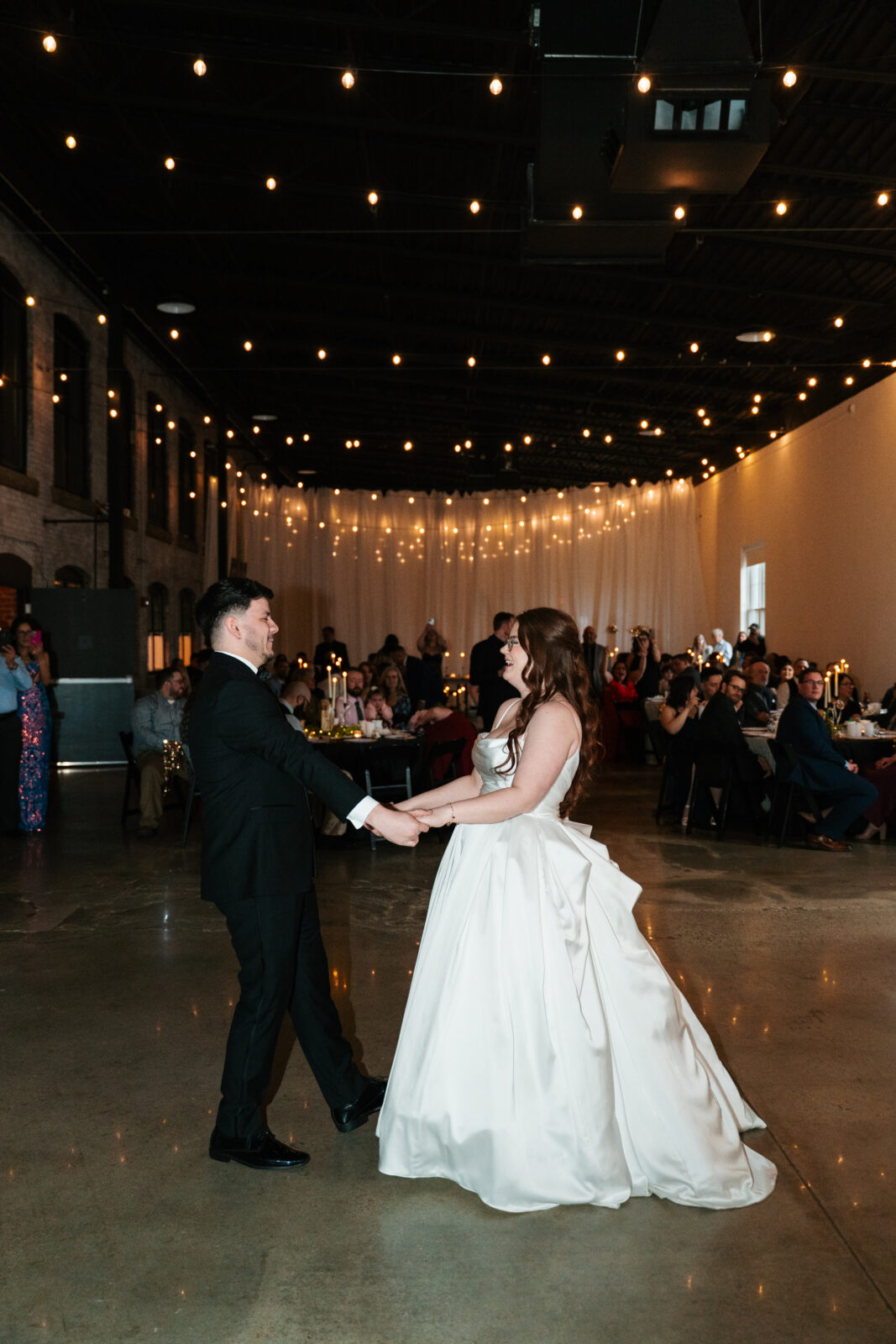 Wedding reception dance floor with guests dancing, including friends in blow-up suits, celebrating to Bad Bunny’s music.