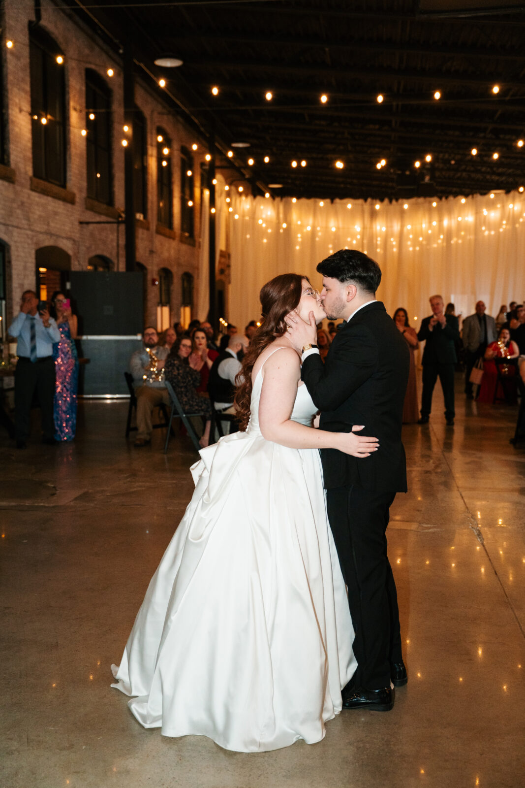 Wedding reception dance floor with guests dancing, including friends in blow-up suits, celebrating to Bad Bunny’s music.