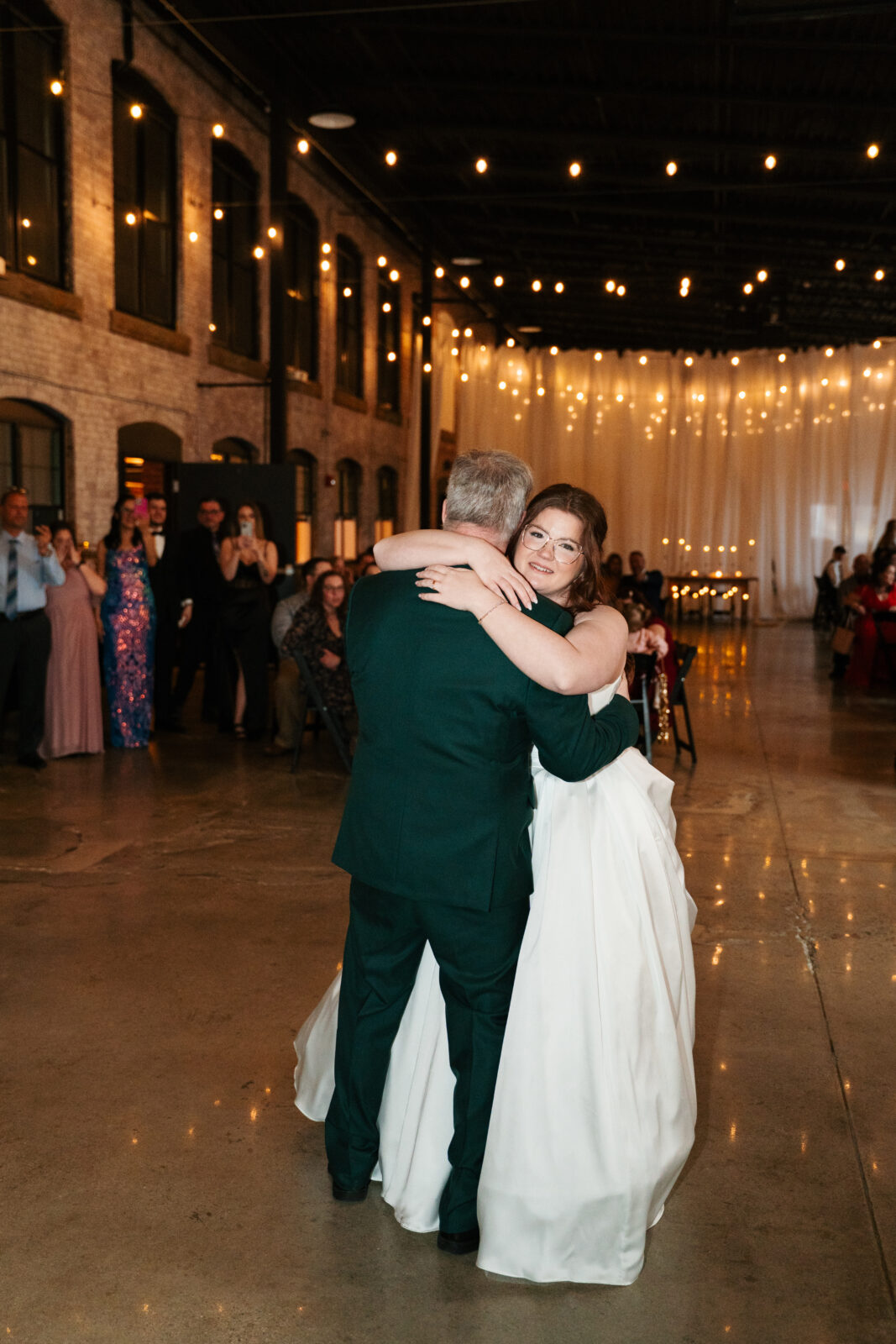 Wedding reception dance floor with guests dancing, including friends in blow-up suits, celebrating to Bad Bunny’s music.
