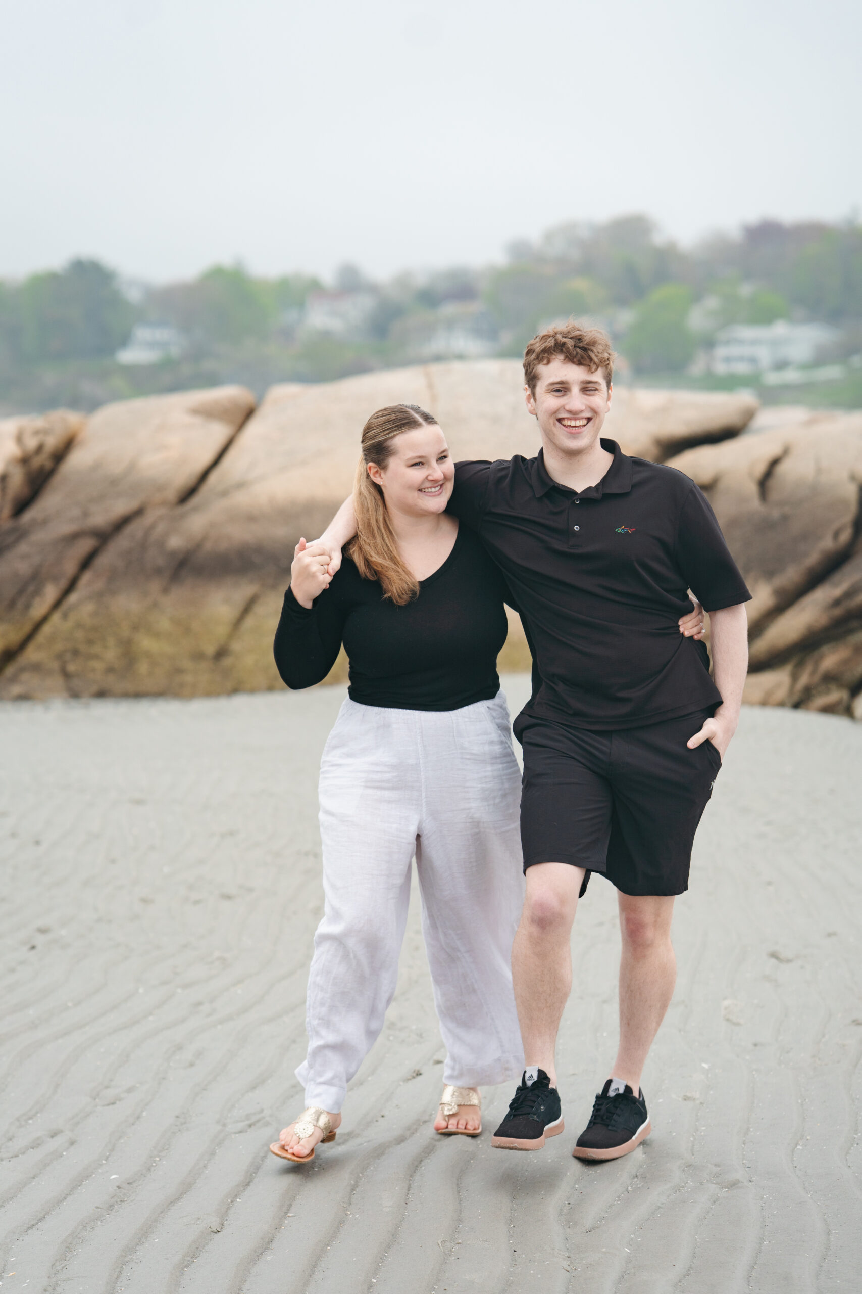 Couple climbing rocks during their beach engagement session