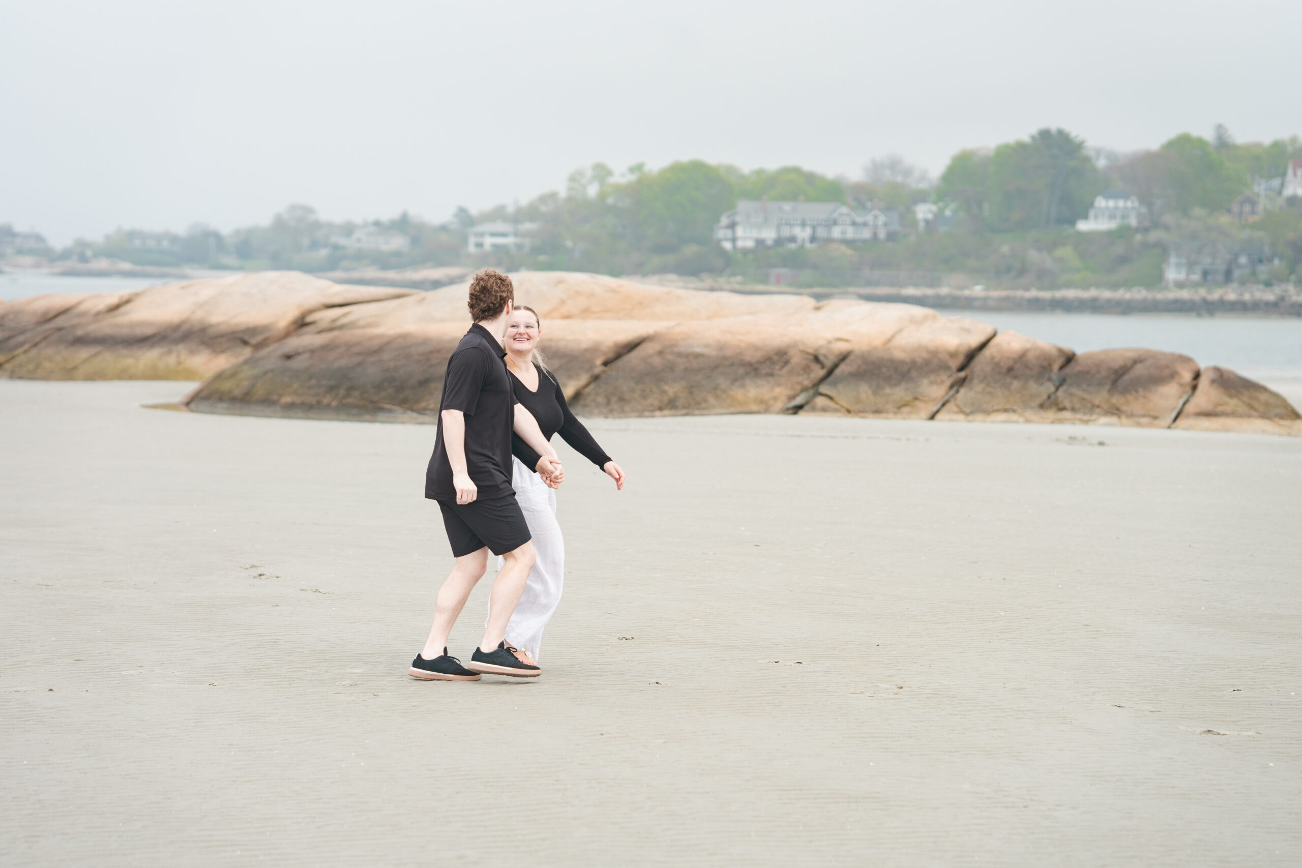 Couple climbing rocks during their beach engagement session
