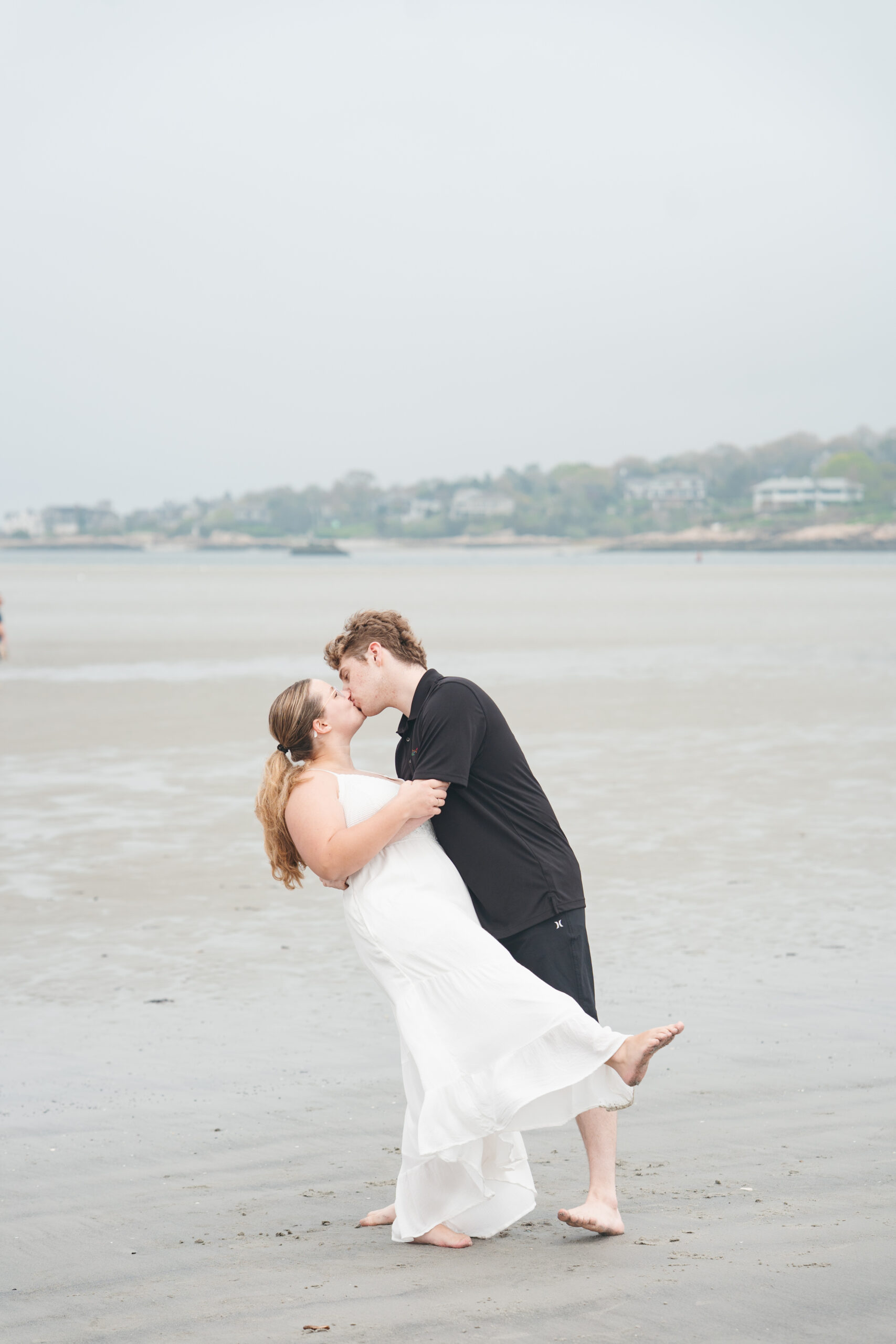 Couple climbing rocks during their beach engagement session