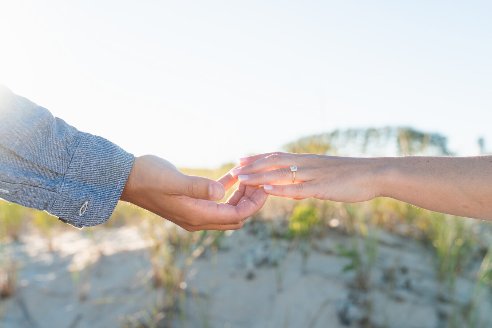 Natural engagement session by the ocean with soft golden hour light.